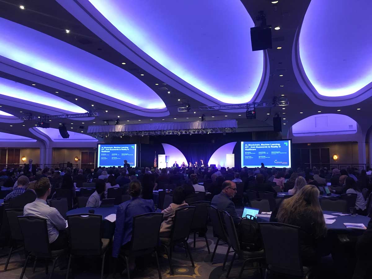 Photo of interior of the 2018 Health Datapalooza showing the stage, speakers, and a large seated audience.