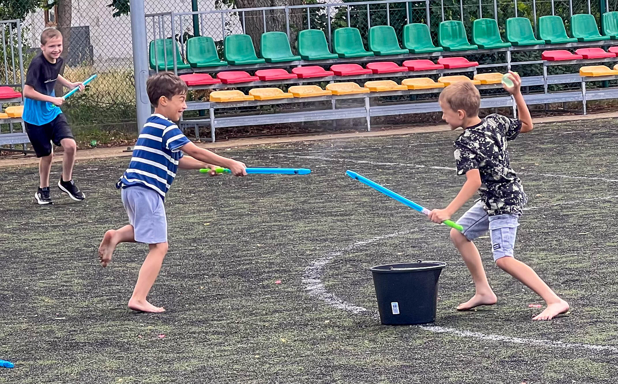 Three boys at the summer camp, grinning during a water balloon fight.