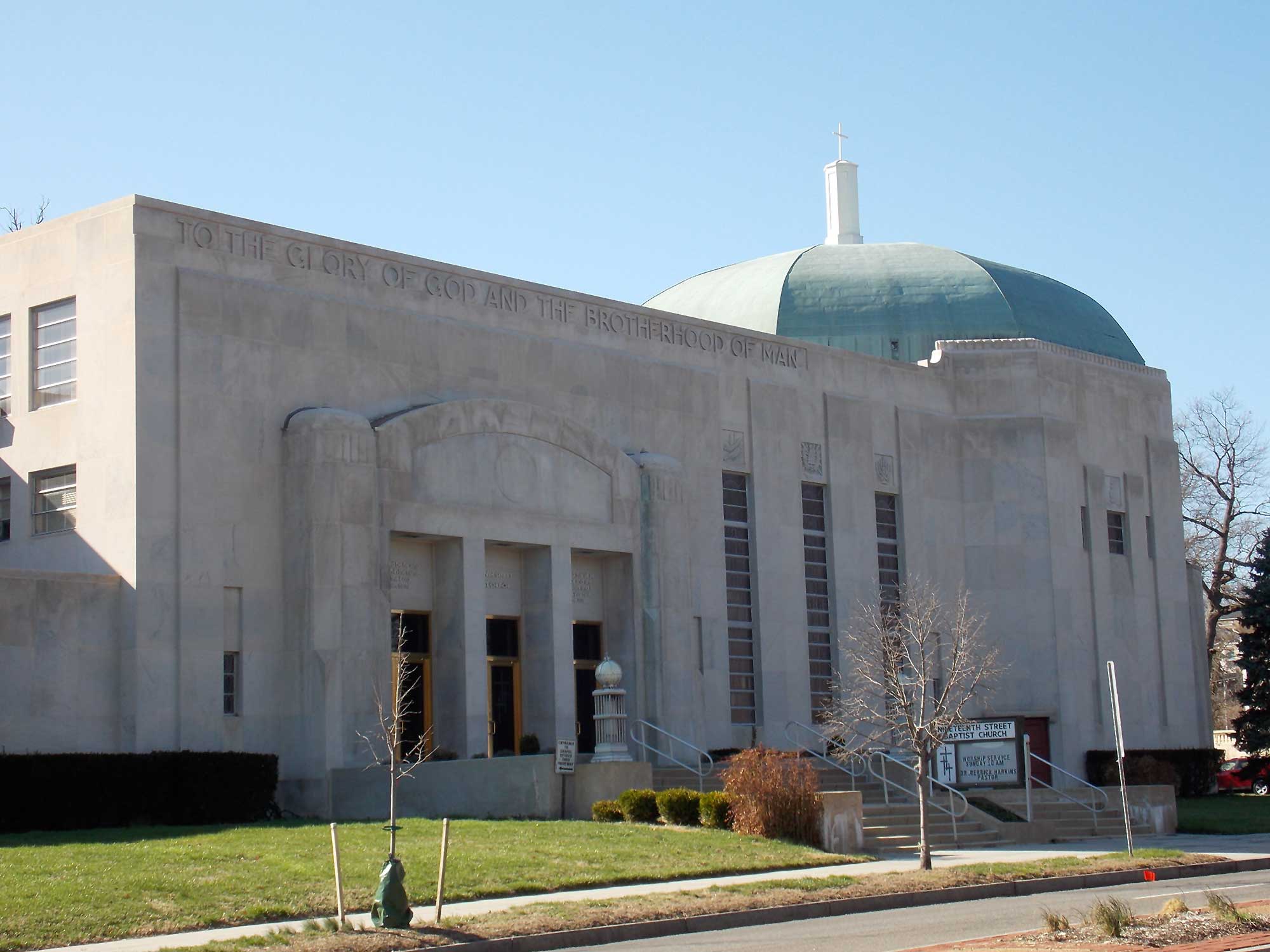 The Nineteenth Street Baptist Church, a rectangular building made of grey limestone with a multi-sided rounded green dome on the right. An inscription reads “To the glory of God and the brotherhood of man.